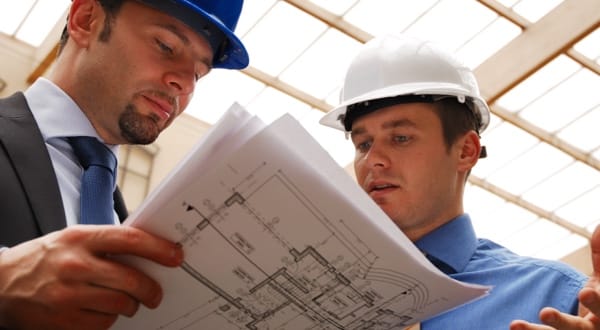 Chef de chantier en casque blanc consultant des plans de construction.