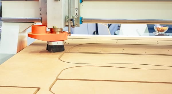 Machine CNC découpant des formes précises dans une planche de bois.