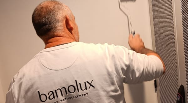 Peintre en train d’appliquer de la peinture sur un mur, portant un t-shirt Bamolux.